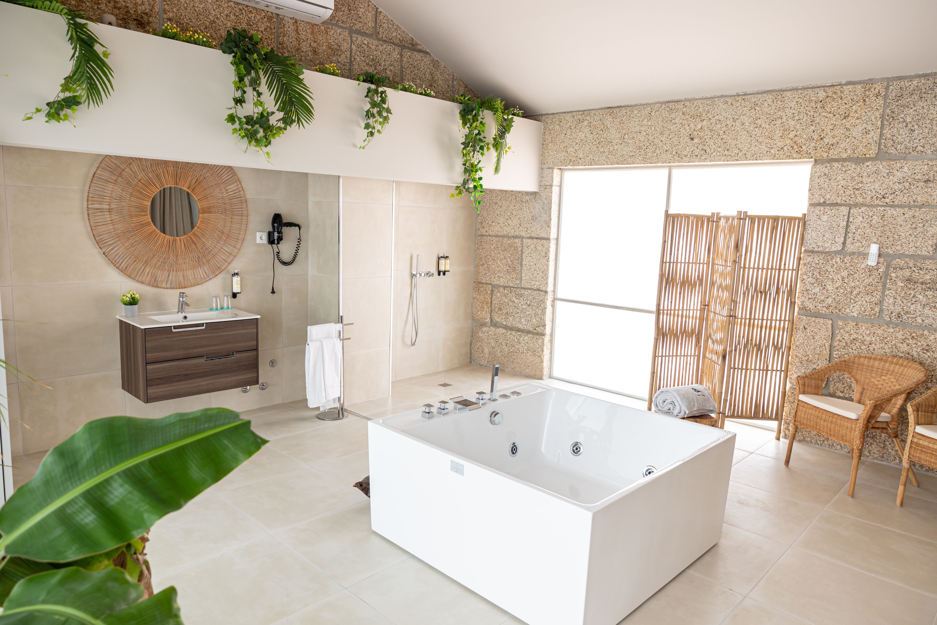 A modern bathroom with a large bathtub, a round mirror, a vanity with a sink, and a shower area.