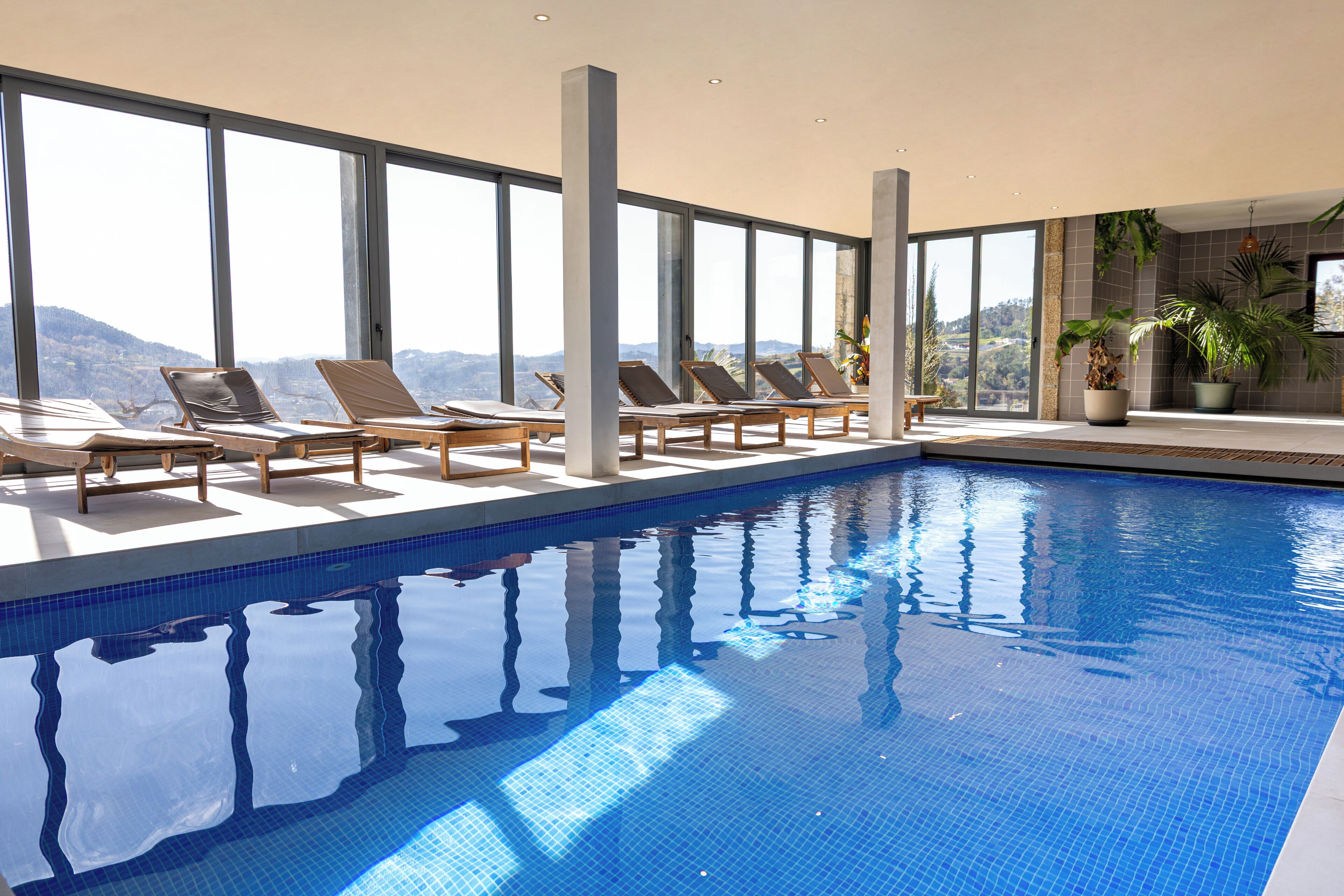 Une piscine dotée de chaises longues et de grandes fenêtres.