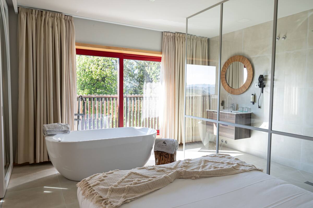 A modern bathroom with a freestanding bathtub, a glass shower enclosure, and a large mirror.