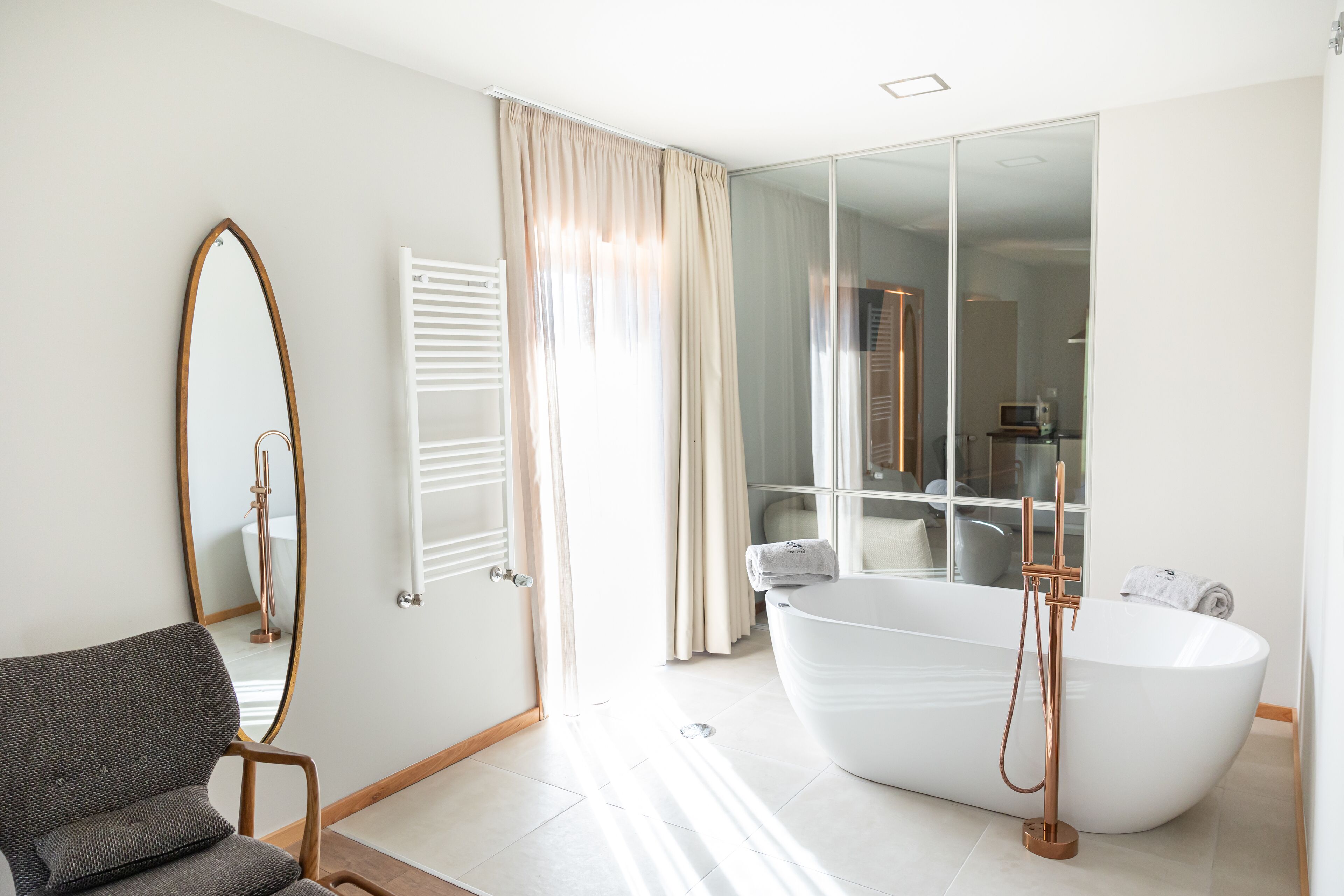 Une salle de bain moderne avec une baignoire sur pieds, un grand miroir et un coin salon.