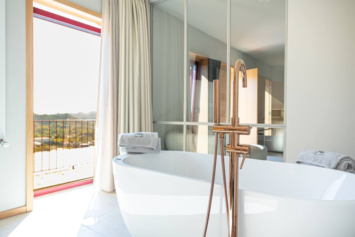 A modern bathroom with a large bathtub, a glass shower enclosure, and a view of the outdoors.