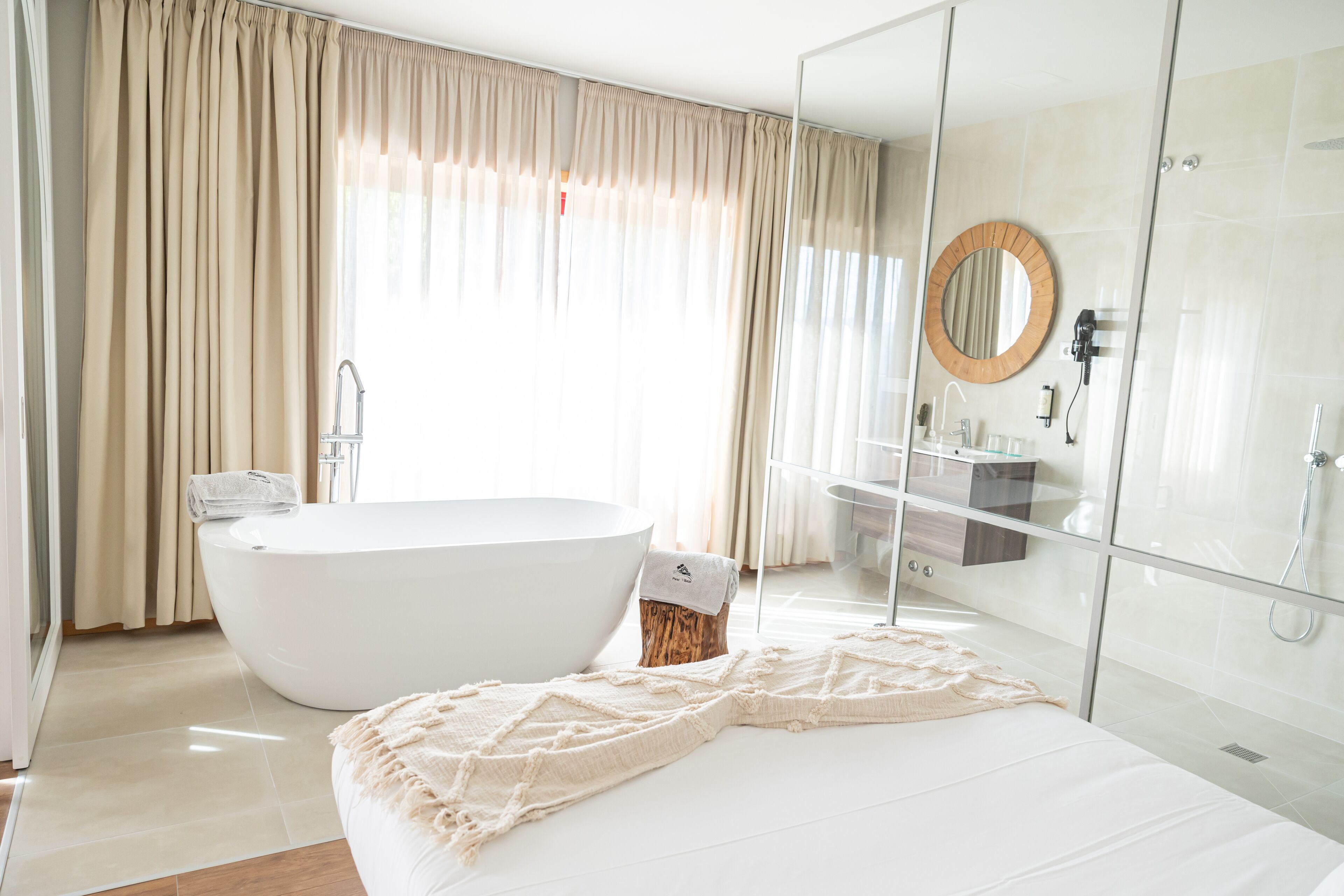 A modern bathroom with a freestanding bathtub, a glass shower enclosure, and a large mirror.