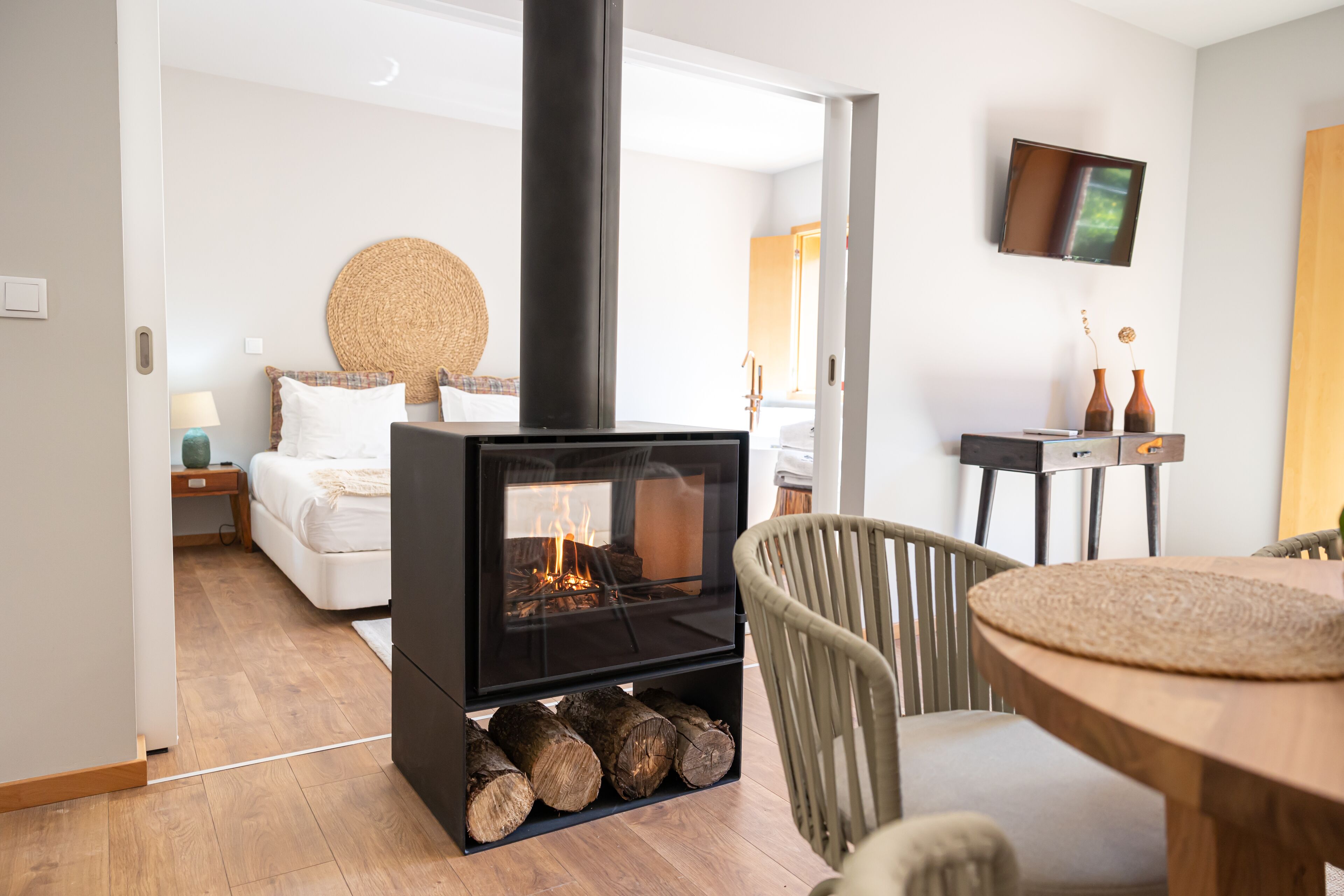 A modern living room with a wood-burning stove, a comfortable sofa, and a dining area.