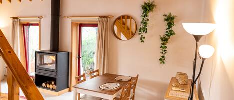 Una habitación acogedora con techo de madera, chimenea, una mesa de comedor con sillas y una lámpara.