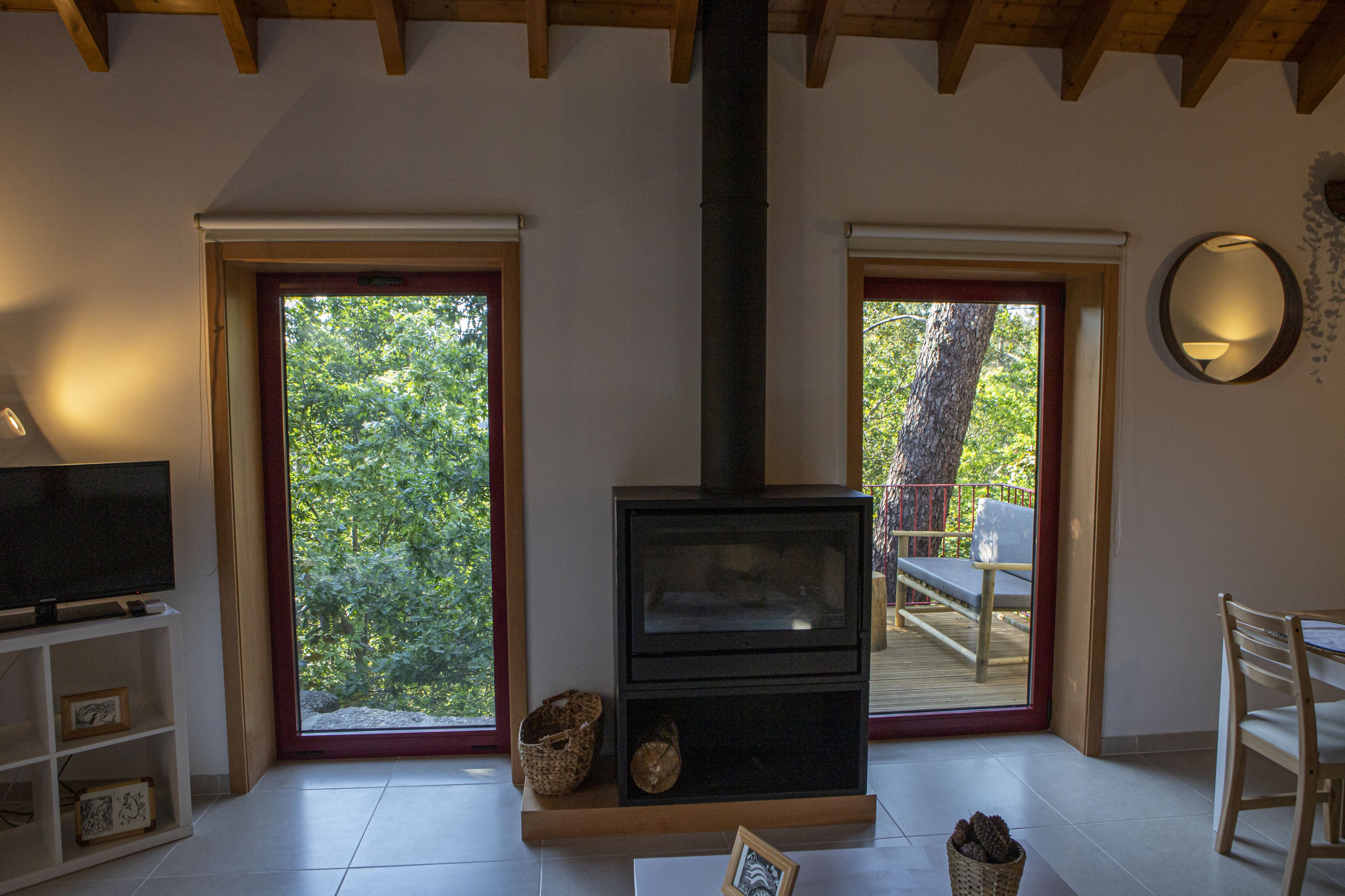 Ein gemütlicher Wohnraum mit Kamin, Fernseher und einem großen Fenster mit Blick ins Freie.