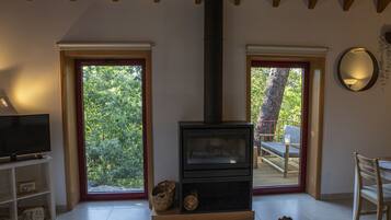 Ein gemütlicher Wohnraum mit Kamin, Fernseher und einem großen Fenster mit Blick ins Freie.