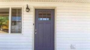 A house with a dark gray front door, a window with a view, and a welcome mat.