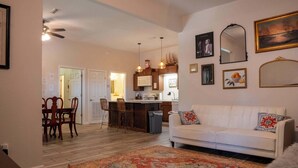 A living room with a white sofa, a patterned rug, and a dining area with wooden chairs and a table.