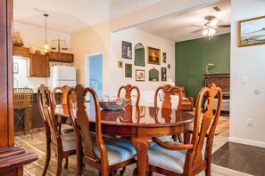 A dining area with a round table, wooden chairs, and a kitchen in the background.