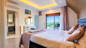 A modern hotel room with a large bed, a bathroom with a sink, and a balcony with a view. - Alanya Luxury Villas (Alanya)