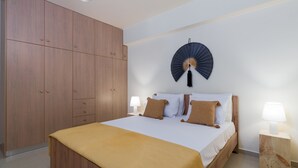 Ein Schlafzimmer mit einem großen Bett, einem Holzschrank und einem Wandventilator.