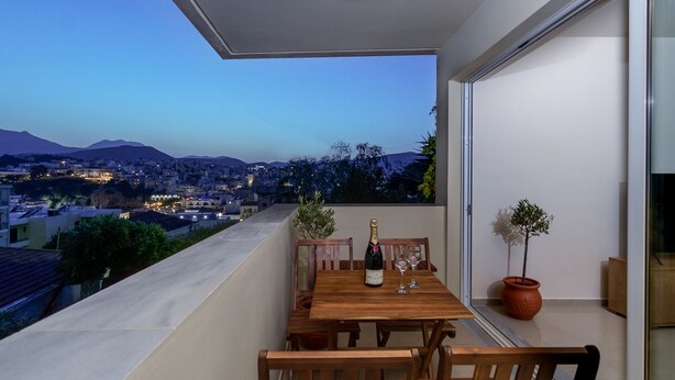 Ein Balkon mit einem Holztisch, gedeckt für zwei Personen, einer Champagnerflasche und zwei Gläsern.