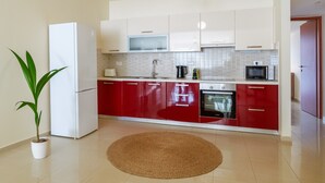 Eine moderne Küche mit weißen und roten Schränken, einer Mikrowelle, einem Toaster und einem Wasserkocher.