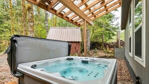 A hot tub under a wooden pergola in a wooded area. - Hart Haus at Stevens Pass- spacious w/ hot tub, EV charger, close to hikes! (Skykomish)