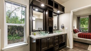 A bathroom with a large mirror, dark wood cabinets, and a glass bowl sink. - Hart Haus at Stevens Pass- spacious w/ hot tub, EV charger, close to hikes! (Skykomish)