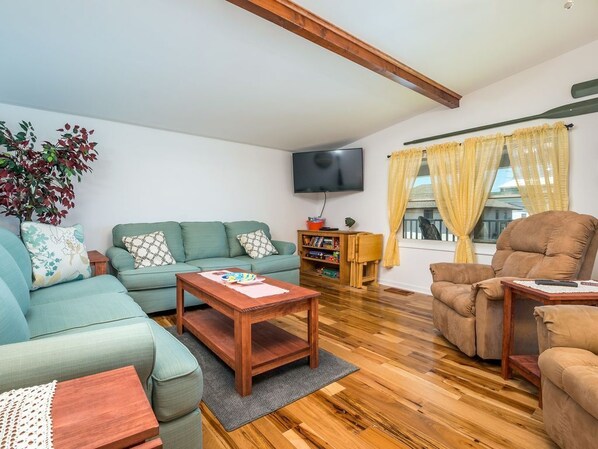 A living room with a sofa, armchair, wooden coffee table, and a television.