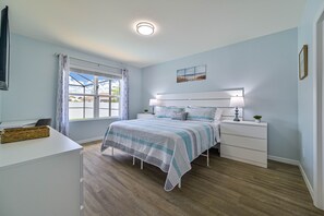 Un dormitorio con cama, mesitas de noche, un escritorio y una ventana con cortinas.