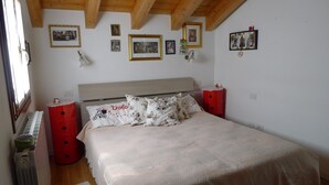 Ein Schlafzimmer mit einem Bett, roten Nachttischen und einer Holzbalkendecke.