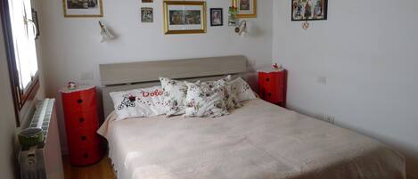 Un dormitorio con cama, mesitas de noche rojas y techo de madera.