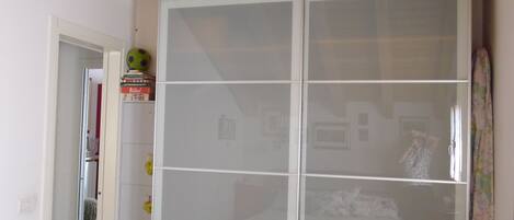 A room with a large glass cabinet, a wooden ceiling, and a door leading to another room.