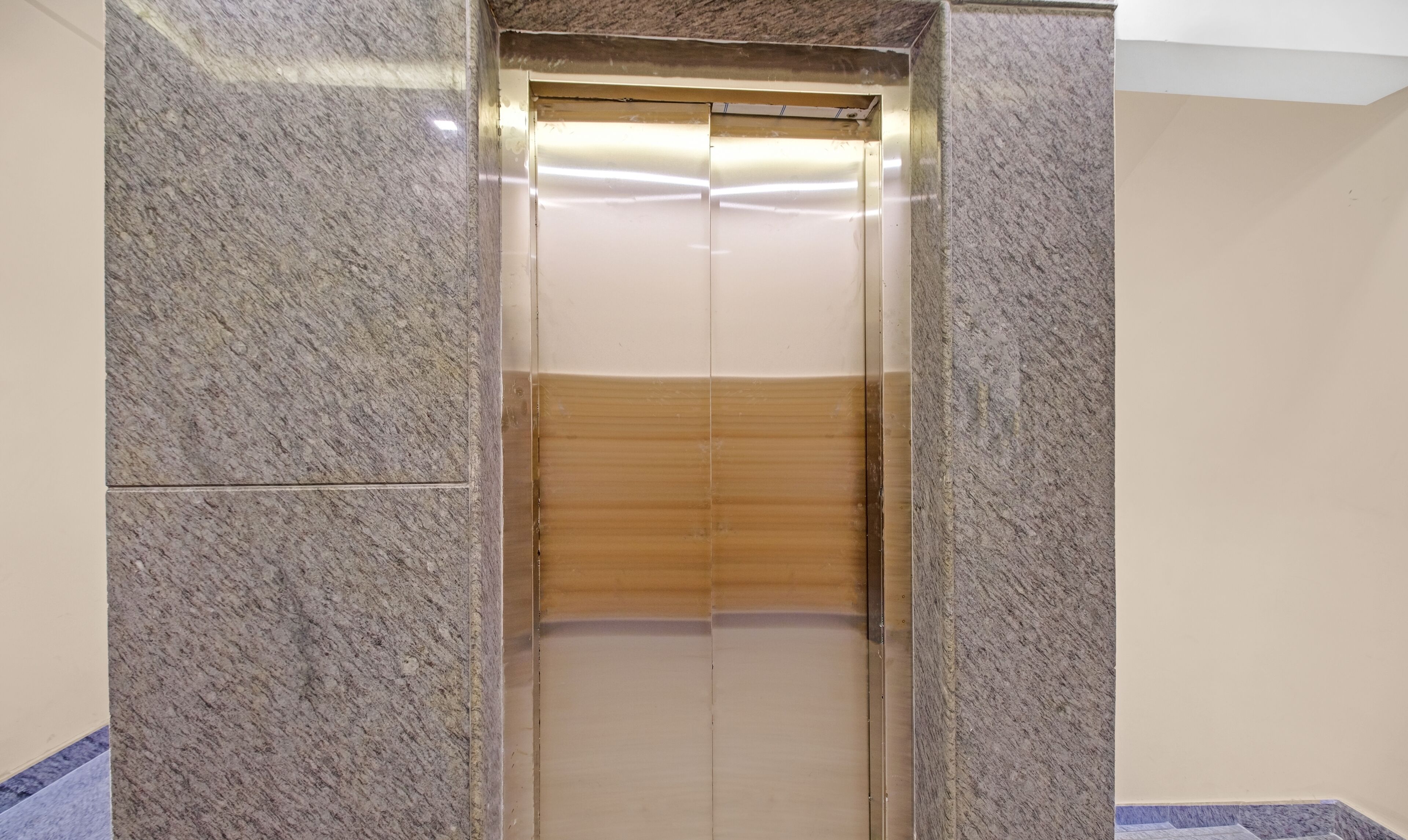 Un ascensor con interior metálico y un panel de madera en la parte inferior.