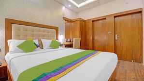 Ein Hotelzimmer mit einem großen Bett, einem Holzschrank und einem kleinen Tisch mit Wasserkocher.