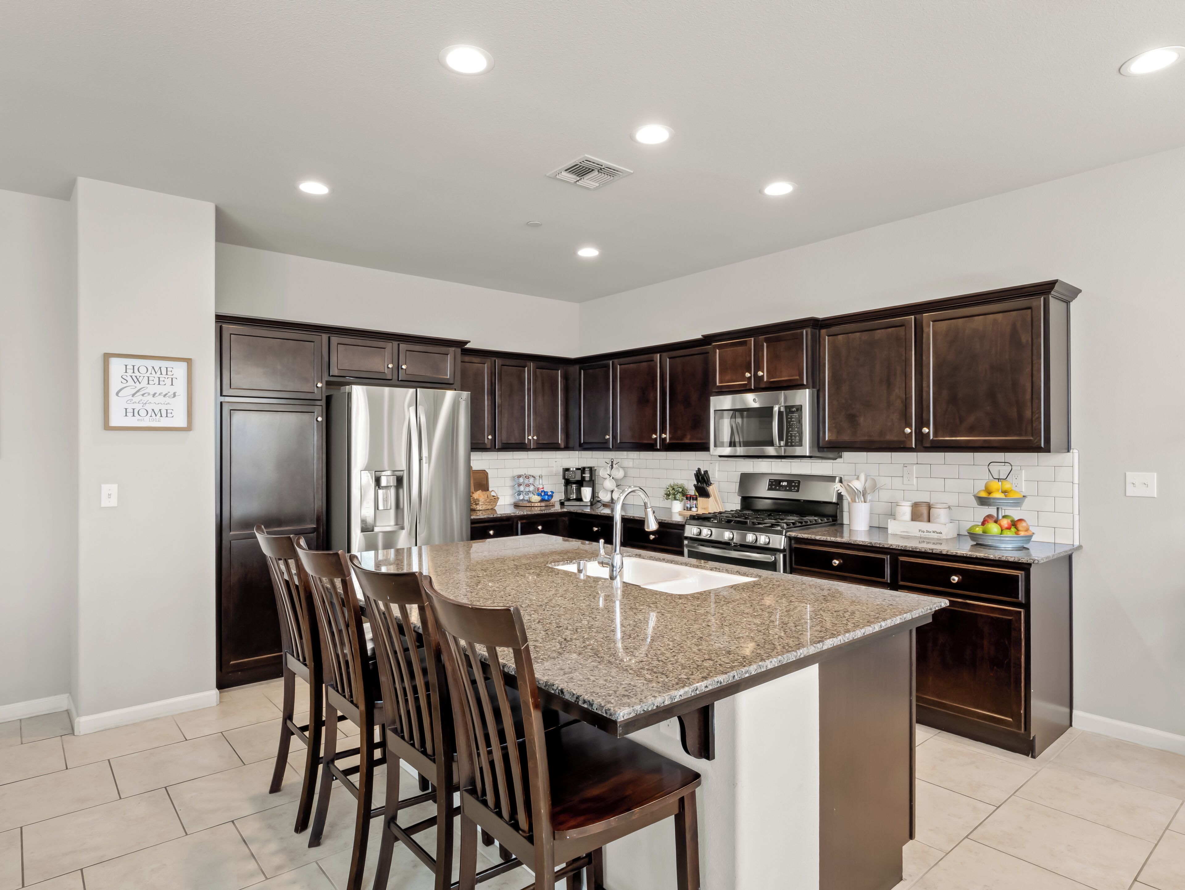 A modern kitchen with dark wood cabinets, stainless steel appliances, and a granite countertop.
