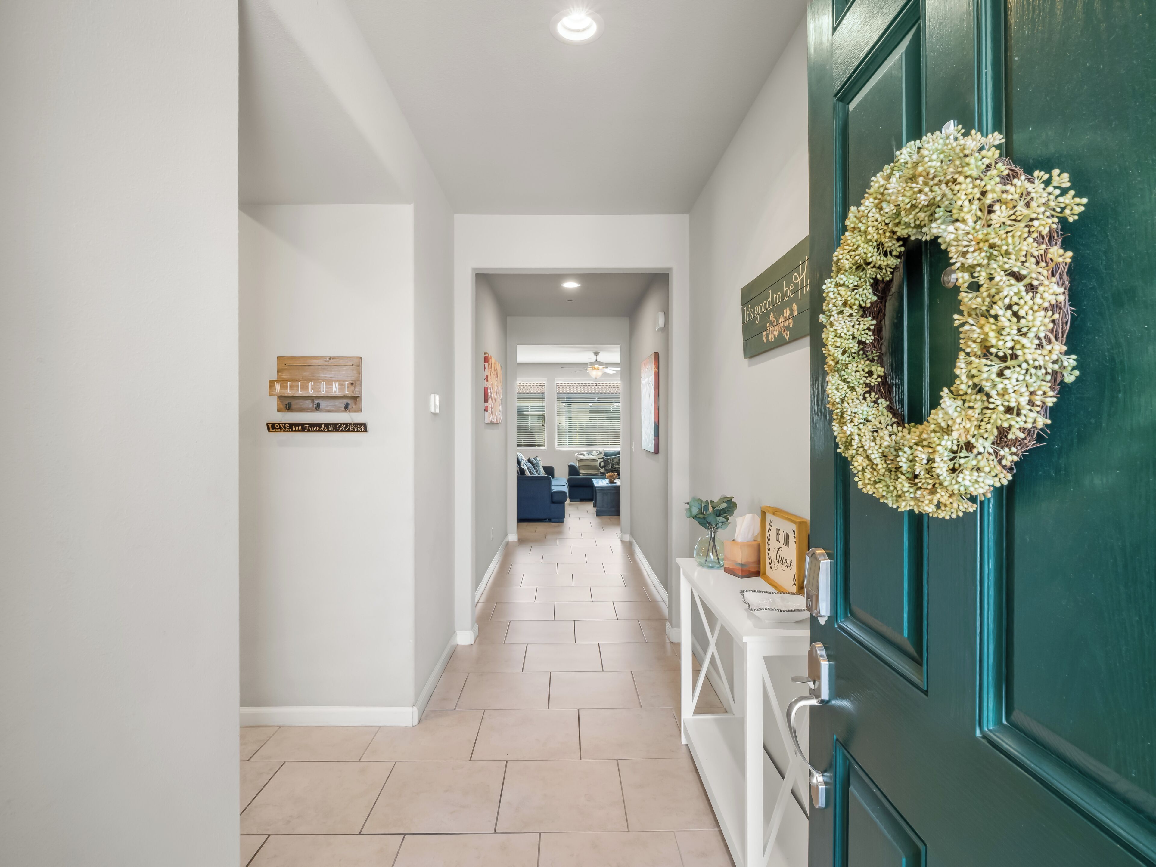 A hallway with a green door, a welcome sign, and a wall-mounted sign.