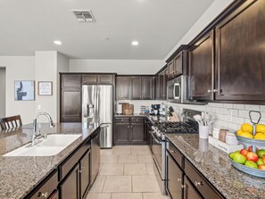 A modern kitchen with dark wood cabinets, stainless steel appliances, and granite countertops.
