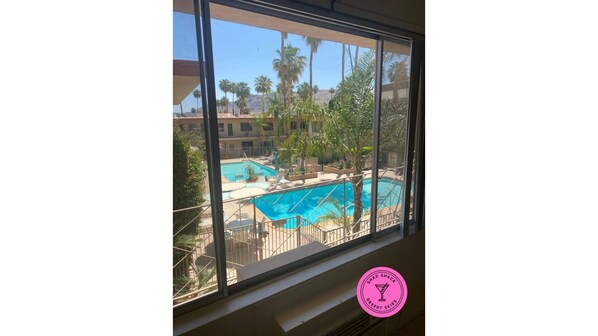 Guests can enjoy a serene view of the pool area surrounded by lush greenery and palm trees.