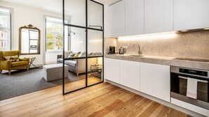 Una cocina moderna con un ventanal grande, horno empotrado y cafetera sobre la encimera.