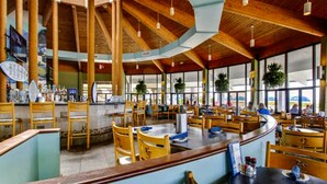 Ein geräumiges Restaurant mit hohen Holzbalkendecken und großen Fenstern.