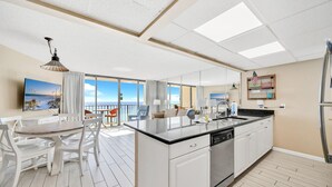 Eine moderne Küche mit einer großen Kochinsel, weißen Schränken und Meerblick.