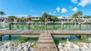 Una marina con muelles de madera, agua tranquila y casas al fondo.