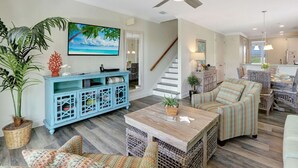 Un salón amplio con un aparador azul, muebles de mimbre y un ventilador de techo.