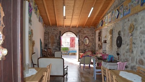 A rustic interior with wooden furniture, stone walls, and colorful artwork. - Nezisin Konagi (Ayvalik)