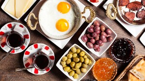 A breakfast setting with eggs, cheese, olives, tomatoes, cucumbers, bread, and beverages. - Nezisin Konagi (Ayvalik)