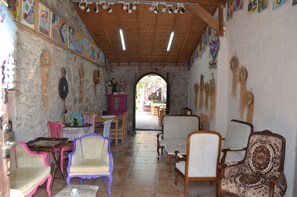 A cozy interior with stone walls, wooden furniture, and colorful artwork. - Nezisin Konagi (Ayvalik)