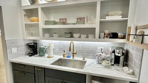 Eine moderne Küche mit doppelter Spüle, Edelstahlgeräten und dekorativen Schalen auf Regalen.