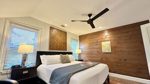 Ein modernes Schlafzimmer mit einem Bett, zwei Nachttischlampen, einem Deckenventilator und einer Wand als Holzdekor.