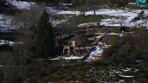 Ein Haus mit Steinfundament, einer Holzterrasse und einem kleinen Garten.