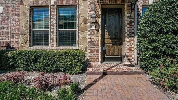 A stone building with a brick facade, a wooden door, and a paved entrance. - Comfortable Chic | Long Term | Legacy (Plano)