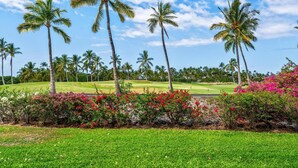 A golf course with palm trees and flowering bushes. - Includes Beach Gear! Spacious lanai with resort views.  #2 Shores at Waikoloa (Waikoloa Beach Resort)