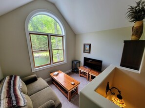 A cozy living room with a large window, a fireplace, a sofa, and a coffee table.