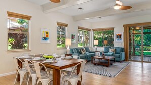 A spacious living room with a wooden dining table, white chairs, a blue sofa, and a coffee table.