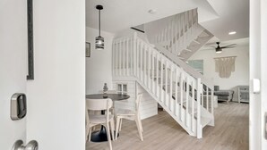 A modern interior with a staircase, a dining area, and a living space. - Beachside Duplex A (Saint Augustine Beach)