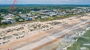 An aerial view of a coastal town with residential buildings, a beach, and a distant view of the ocean. - Beachside Duplex A (Saint Augustine Beach)