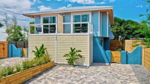 A modern two-story house with a balcony, a wooden deck, and a brick pathway. - Beachside Duplex A (Saint Augustine Beach)