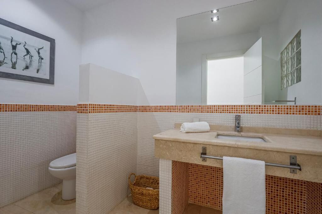 Une salle de bain avec des toilettes blanches, un lavabo avec une serviette et un miroir.