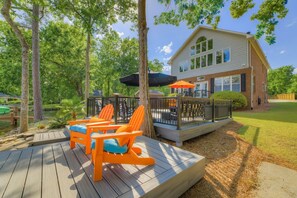 A wooden deck with outdoor seating and a view of a house with a brick exterior.